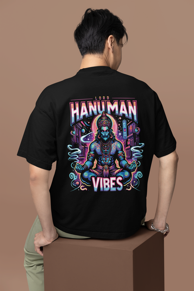 Person wearing a black t-shirt with a colorful 'Hanuman Vibes' design on the back against a brown background