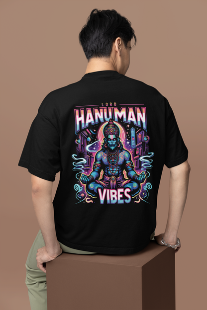Person wearing a black t-shirt with a colorful 'Hanuman Vibes' design on the back against a brown background