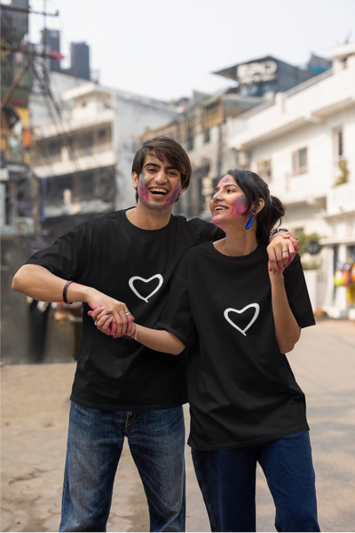 Two people wearing black t-shirts with white hearts, standing together on a street.