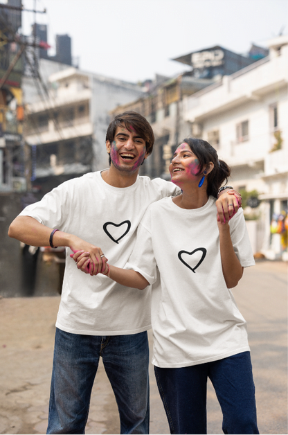 Two people wearing white t-shirts with black hearts, standing on a street.